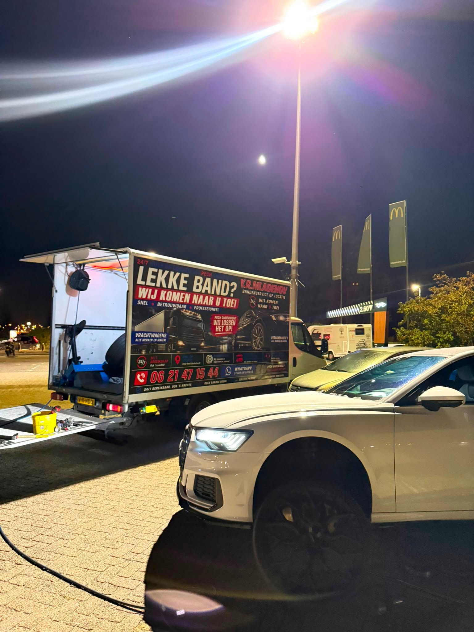 Lekke band 's avonds vervangen op een parkeerplaats bij een wegrestaurant